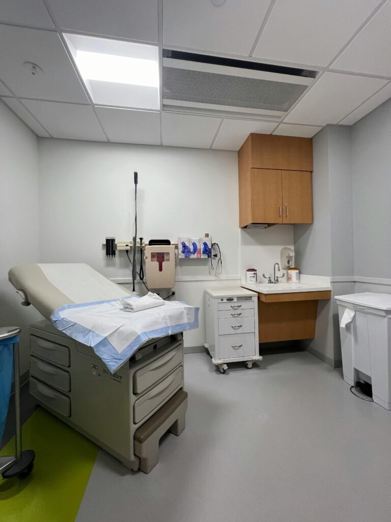 Clean and organized medical examination room with essential equipment and furniture.